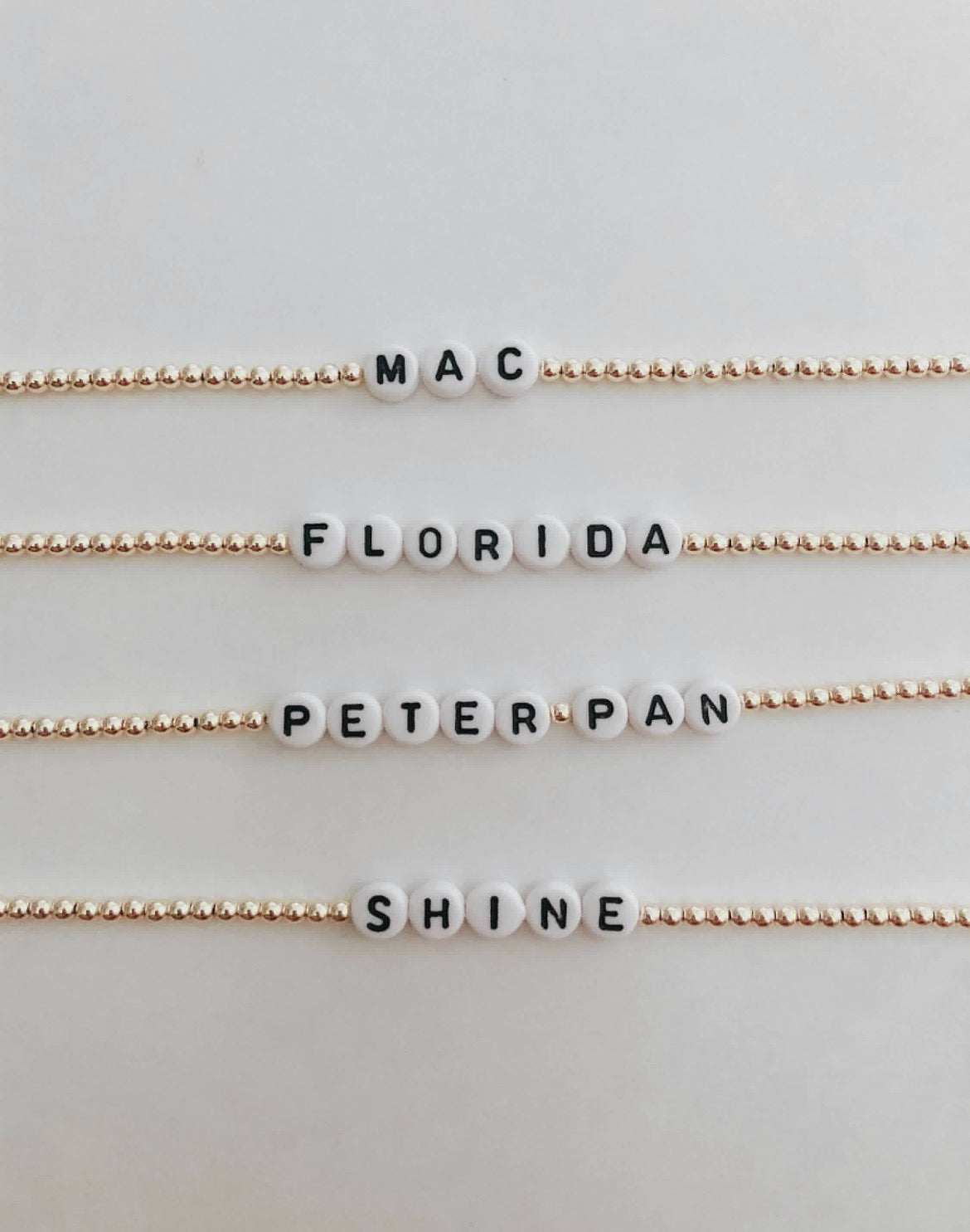 these bracelets are small gold beads with white and black letter beads that are able to spell out whatever you decide.