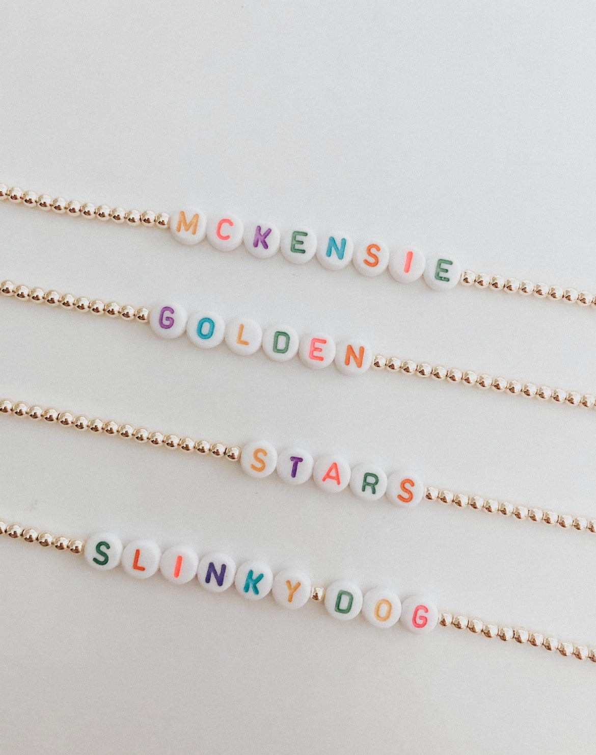 these bracelets are small gold beads with white beads that have different color letters that are able to spell out whatever you decide.