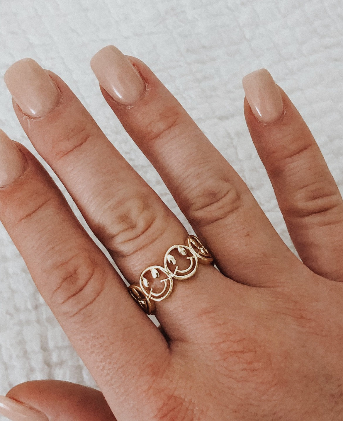 This ring is multiple smiley faces together in a line. The smiley faces gold outlined, but hollow in the middle. It is open in the back and adjustable.