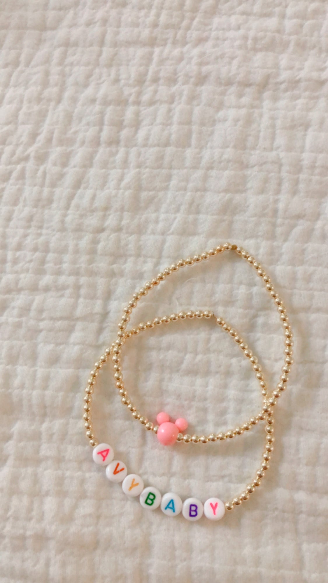 these bracelets are small gold beads with white beads that have different color letters that are able to spell out whatever you decide.