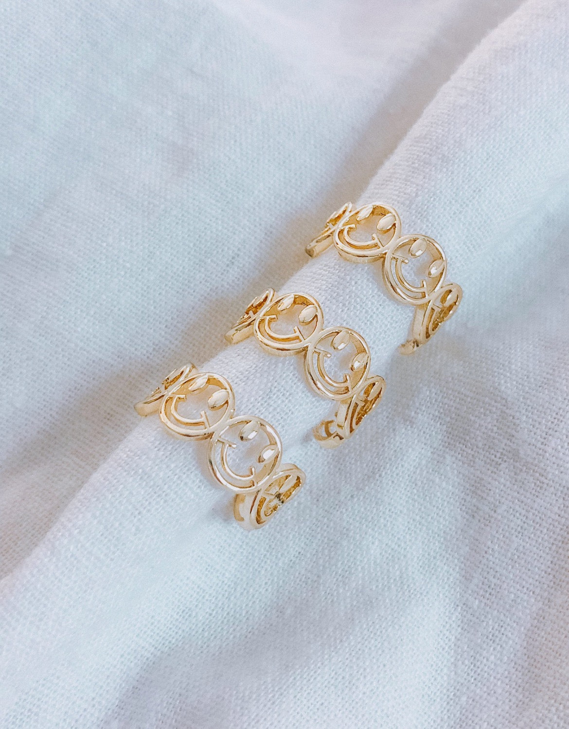 This ring is multiple smiley faces together in a line. The smiley faces gold outlined, but hollow in the middle. It is open in the back and adjustable.