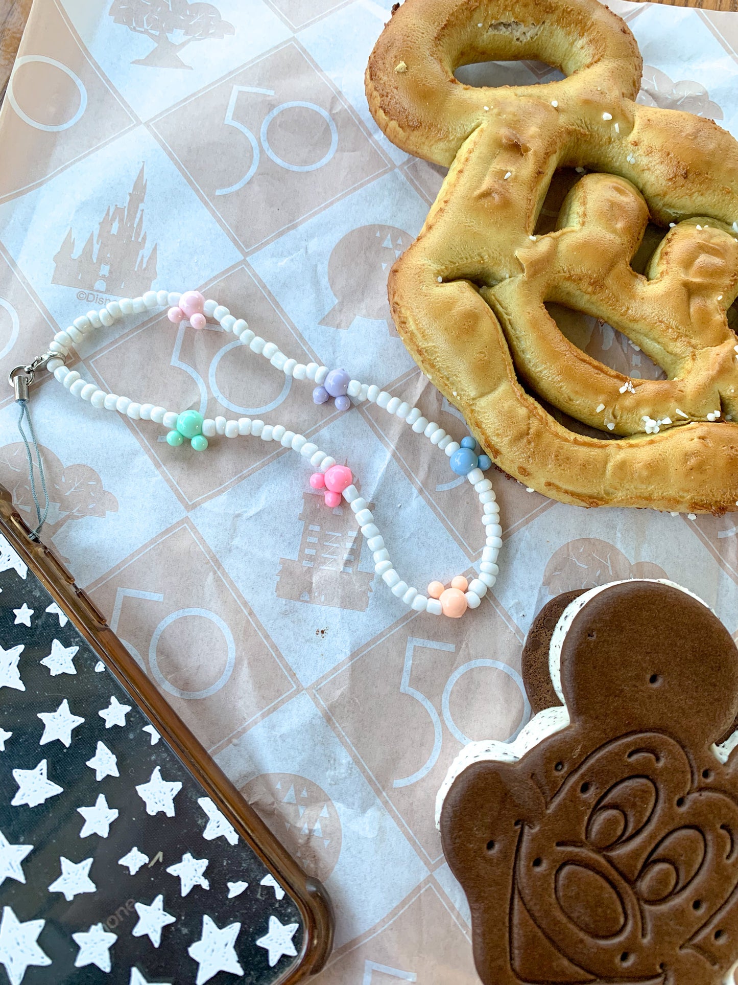 The dreamer phone charms are small white beads with different colored mickey mouse heads spread along the charm. It has about six mickey mouse heads on it. it connects to the phone with a black strand with gold clasps.