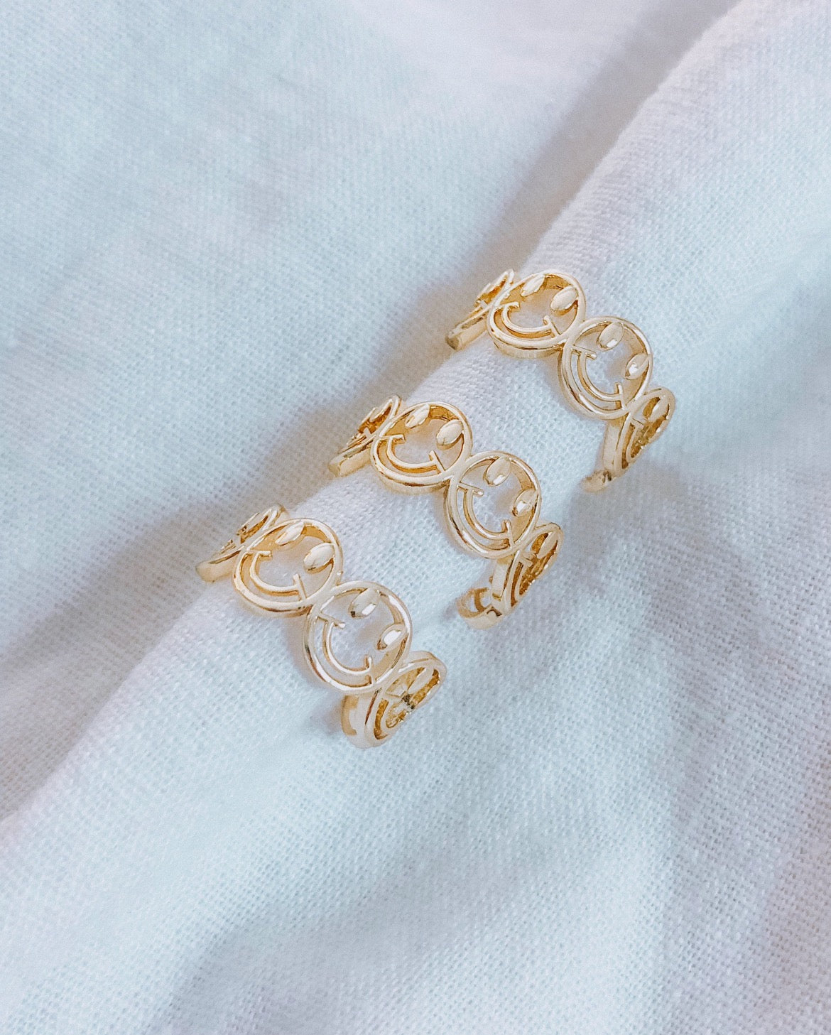 This ring is multiple smiley faces together in a line. The smiley faces gold outlined, but hollow in the middle. It is open in the back and adjustable.
