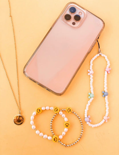 The dreamer phone charms are small white beads with different colored mickey mouse heads spread along the charm. It has about six mickey mouse heads on it. it connects to the phone with a black strand with gold clasps. 